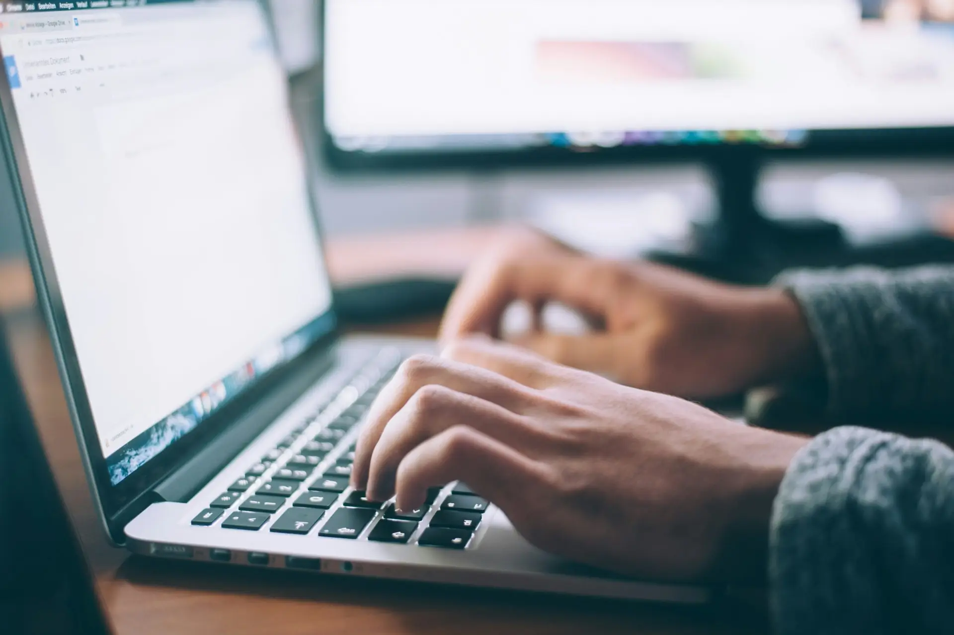 Mains utilisant un ordinateur portable pour mettre à jour un logiciel, illustrant l’importance de vérifier la version d’Adobe Acrobat Reader après une faille de sécurité.
