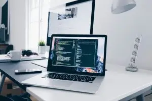 Poste de travail moderne avec ordinateur portable affichant du code HTML/CSS, illustrant un environnement numérique sécurisé