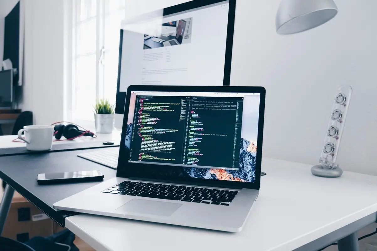 Poste de travail moderne avec ordinateur portable affichant du code HTML/CSS, illustrant un environnement numérique sécurisé