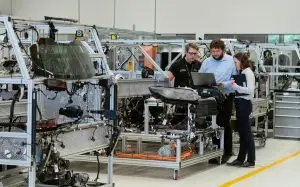 Employés consultant un ordinateur portable à proximité d’équipements de production dans une usine
